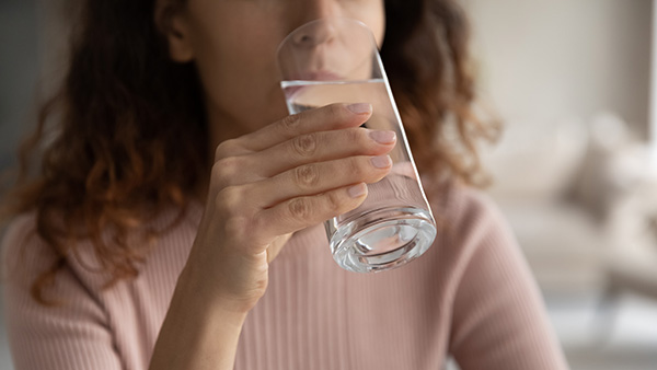 Eine Frau trinkt aus einem Glas Wasser